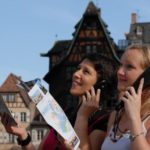 Visite commentée à pied avec un audio-guide. Deux personnes visitant Strasbourg avec un audio guide à l'oreille et une carte à la main.